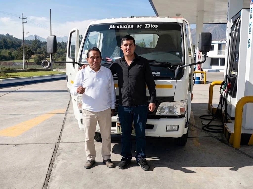 Padre e hijo de la familia Otiniano frente a una de sus unidades